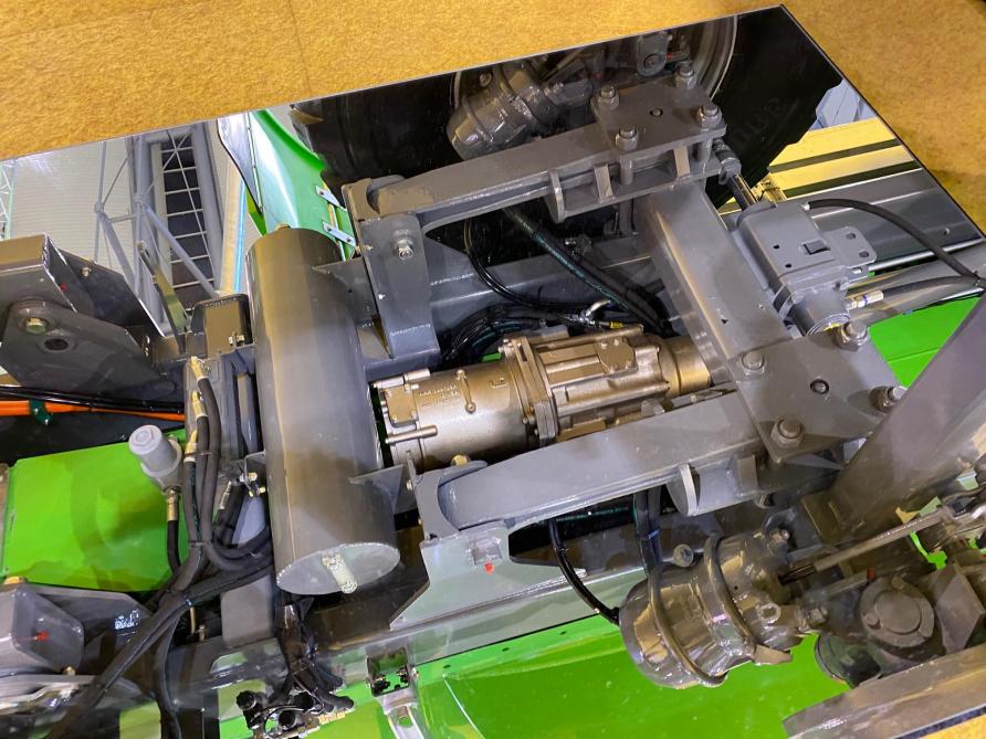 L’installation d’un miroir sous la machine exposée permet de visualiser l’intégration  du moteur électrique et de la boîte de transfert au niveau du châssis,  au-dessus du premier essieu.