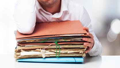 bored-man-looking-pile-papers-with-one-hand-his-forehead