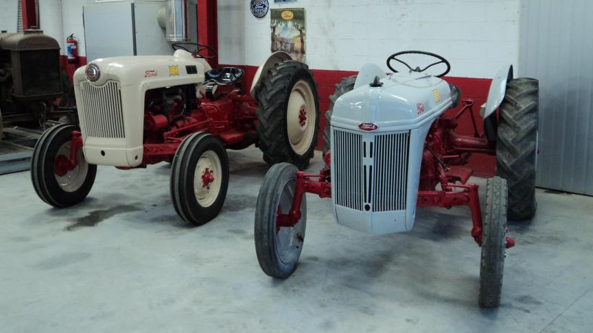 Le Ford 8N (à droite) côtoie directement son successeur, le Ford NAA  Golden Jubilee, sous le toit du hangar abritant une partie de la collection.